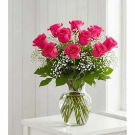 Pink roses arranged in a clear glass vase with white filler flowers.