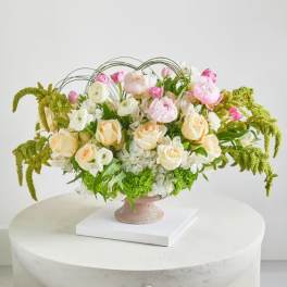 Pastel floral arrangement in a pedestal vase with arching greenery