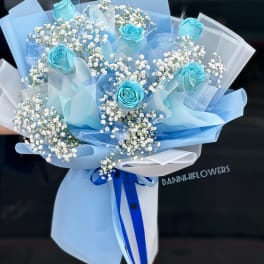Bouquet of blue roses and white baby's breath wrapped in pale blue paper