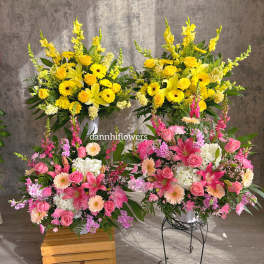 Two large floral arrangements with yellow and pink blooms in white containers