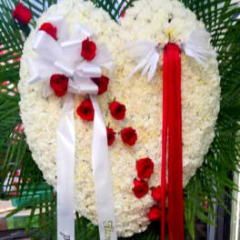 Heart-shaped floral tribute with red and white flowers and long ribbons