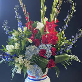 Tall red, white, and blue floral arrangement in a white vase