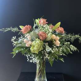 Peach roses and lilies in a clear glass vase