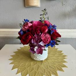 Colorful bouquet of roses, hydrangea, and blue flowers in a white vase