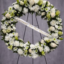 White funeral wreath with roses, lilies, and daisies on a stand