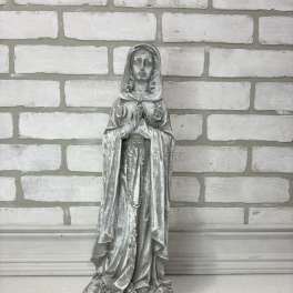 Weathered gray religious statue of a praying woman on a base