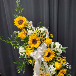 Standing floral spray with sunflowers, white blooms, and a white ribbon