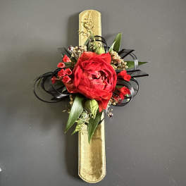 Red floral corsage on a gold ribbon band with black ribbon loops