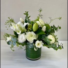 White flowers arranged in a green vase with airy greenery