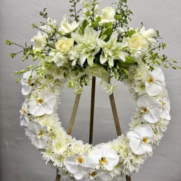 White floral heart wreath on a stand with orchids and lilies