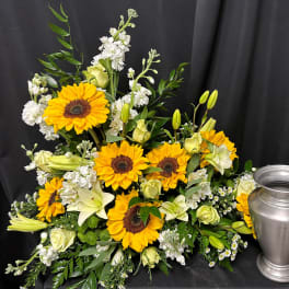 Sunflower and white floral arrangement beside a silver urn