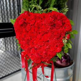 Heart-shaped red floral arrangement with ribbon streamers