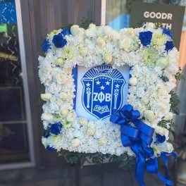 Square floral wreath with white and blue flowers around a Greek crest