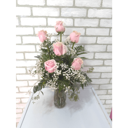 Pink roses arranged in a clear glass vase with baby's breath