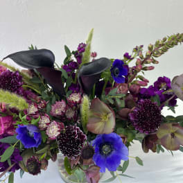 Purple and blue floral arrangement in a clear glass vase