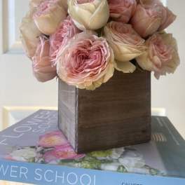 Pink and cream roses arranged in a wooden box