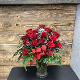 Red rose bouquet in a clear glass vase with a red ribbon