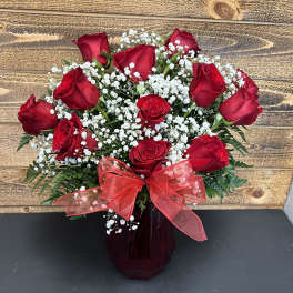 Red roses with white baby's breath in a dark vase and red bow