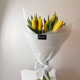 Bouquet of yellow tulips wrapped in white paper with a satin bow