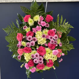 Standing spray of pink roses and mixed blooms on a metal easel