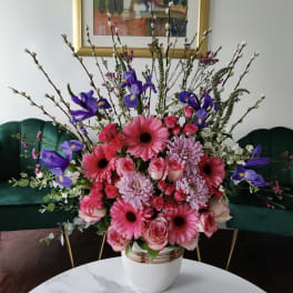 Pink and purple mixed flower arrangement in a white vase