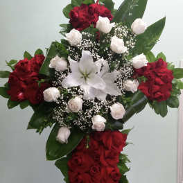 Cross-shaped floral arrangement of red and white roses with a white lily