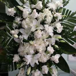 Tall white funeral spray with lilies, roses, and chrysanthemums