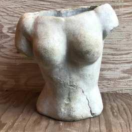 Torso-shaped ceramic planter on a wooden surface