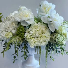 White floral arrangement in a white pedestal vase