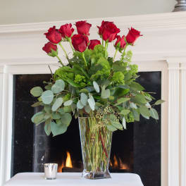 Tall vase arrangement of red roses with greenery