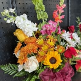 Mixed bouquet in a yellow vase with sunflowers, roses, and snapdragons