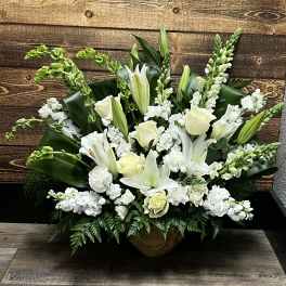 White lilies and roses arranged in a low urn with greenery