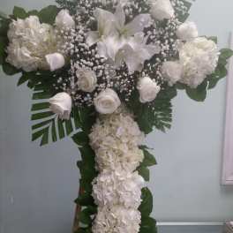 White floral cross arrangement with roses, lilies, and hydrangeas
