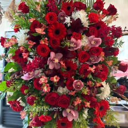 Large red floral standing spray with roses, gerberas, orchids, and white mums