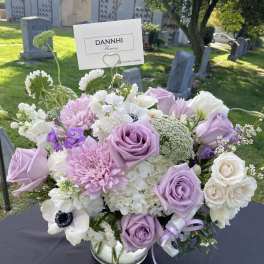 Lavender and white floral arrangement in a glass vase with a card pick