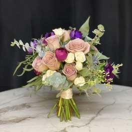 Bouquet of blush and purple roses with eucalyptus on a marble surface