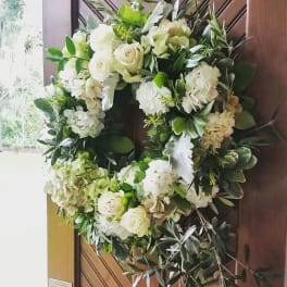 White and cream rose and hydrangea wreath hanging on a wooden door