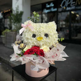 Cat-shaped flower arrangement with white blooms and red roses in a pink box