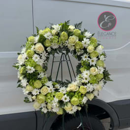 Large floral wreath of white and green flowers on a stand