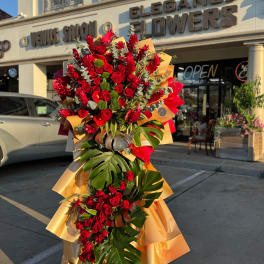 Tall bouquet of red roses and tropical leaves wrapped in gold paper