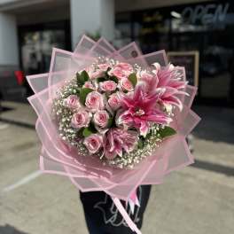 Pink rose bouquet with large pink lilies wrapped in translucent pink paper