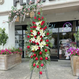 Tall standing floral spray with red roses and white lilies on a metal easel
