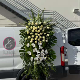 Tall white rose and orchid standing spray with large tropical leaves