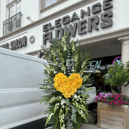 Standing floral tribute with yellow roses arranged in a heart shape
