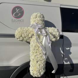 White floral cross with a silver ribbon attached to a van