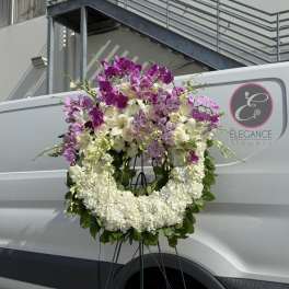 Large floral wreath of white and purple orchids on a stand