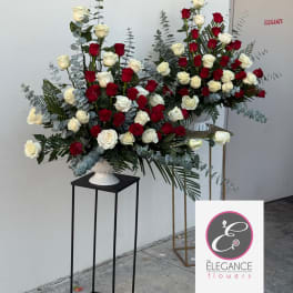 Large red and white rose arrangements in white vases on tall stands