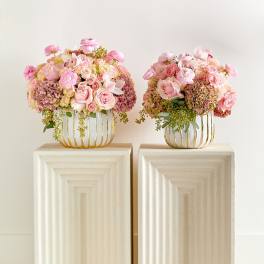 Two pink floral arrangements in gold wire vases on pedestals