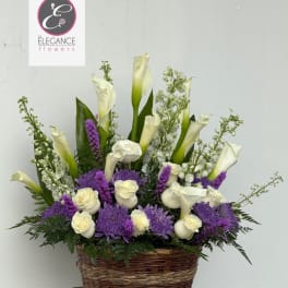 Basket arrangement of white calla lilies, roses, and purple flowers