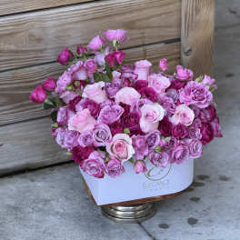Pink and lavender rose bouquet in a white box on a metal stand